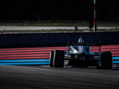 A single-seater race car cornering on a circuit with painted kerbs