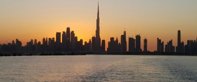 Dubai skyline with the Burj Khalifa glowing across the water at sunset