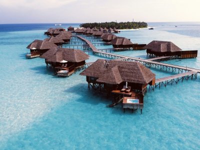 A wooden overwater villa on clear turquoise water in the Maldives